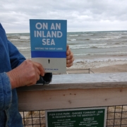 Joan Donaldson holds her copy of On An Inland Sea: Writing the Great Lakes at Pier Cove Park on the Lake Michigan shore.